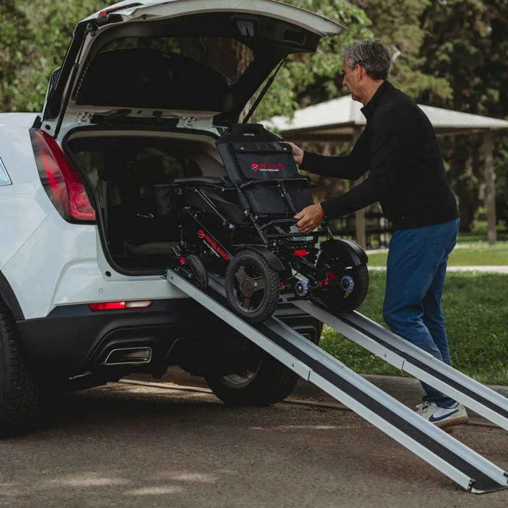 Man using the Travel Buggy lightweight retractable ramps to load a power wheelchair into an SUV.